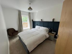 a bedroom with a bed and a chair and a window at KENT, DARTFORD STATION APARTMENTs in Dartford