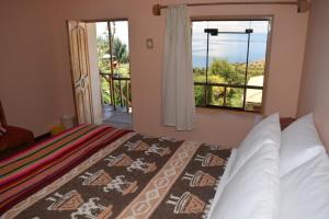 a bedroom with a bed and a large window at Allpa Tika Lodge in Amantani