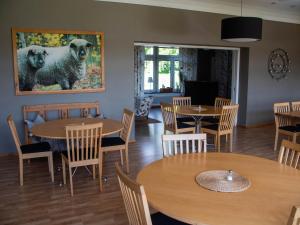 a restaurant with tables and chairs and a painting of two poodles at Vassbo Logi & Event in Falun