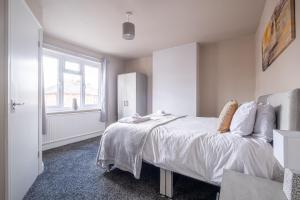 a bedroom with a bed with white sheets and a window at Stunning Home Ideal for Business - Free Parking in Birstall