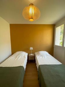 two beds in a room with a lamp and a bed sidx sidx sidx at Panisse - Parking - Clim - Wifi in Cassis