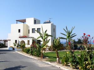 una casa blanca con palmeras y una carretera en Aura Holiday Villas, en Pafos