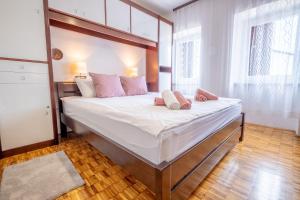 a bedroom with a large bed with white sheets and pink pillows at Villa Sea Valley in Crikvenica