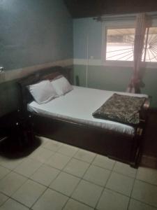 Cama pequeña en habitación con ventana en Grace and favour guest house, en Douala