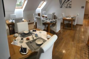 une salle à manger avec des tables en bois et des chaises blanches dans l'établissement Druid House B&B, à Inverness