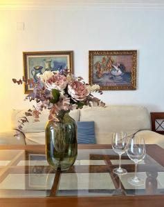 un jarrón de flores en una mesa con dos copas de vino en Encantador piso en Villafranca de Córdoba, en Villafranca de Córdoba