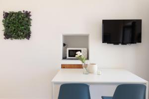 a white table with blue chairs and a tv at Tusa Bay in Castel di Tusa