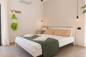 a bedroom with a white bed with a green blanket on it at Tusa Bay in Castel di Tusa