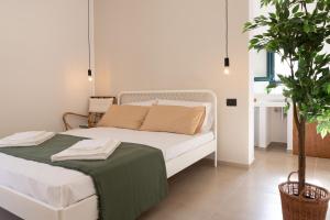 a white bed in a room with a potted plant at Tusa Bay in Castel di Tusa