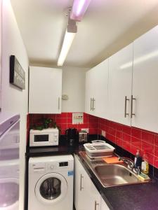 cocina con fregadero y lavadora en White chapel Holiday 2 Bedroom Apartment, en Londres