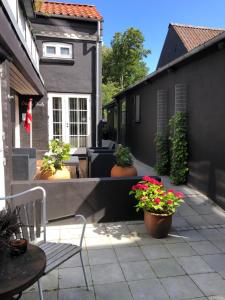 een patio met potplanten en een bank en een huis bij Hus-lejlighed i ejendommens baghus in Odense