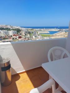 d'une table et de chaises blanches sur un balcon avec vue. dans l'établissement Appartement de Prestige, vue Kasbah, Mer et Vieux Port, à Tanger