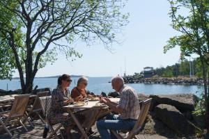 a group of people sitting at a table by the water at Femöre Marina in Oxelösund