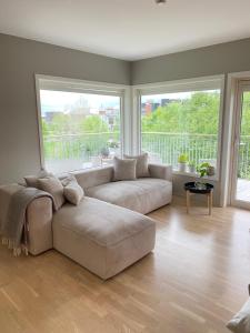 a living room with a couch and a large window at Moderne leilighet, 3 sov, parkering. in Trondheim