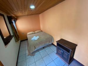 a small bedroom with a bed and a table at Hotel del Ferrocarril in Quetzaltenango