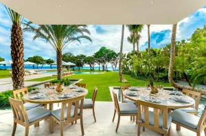 een eetkamer met tafels en stoelen en palmbomen bij Sunny Vacation Villa No 44 in San Rafael del Yuma