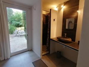 baño con lavabo y puerta corredera de cristal en Hacienda chambre avec petit déjeuner inclus, en Patrimonio