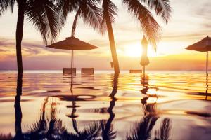 puesta de sol en la playa con palmeras y piscina en Les Jardines d`Artemis (27) en Saint-Tropez