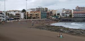 a group of people on a beach with buildings at Kgemelas in Telde