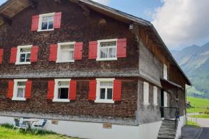 Casa de madera con persianas rojas y montañas en Great old WÄLDERHAUS, en Au im Bregenzerwald