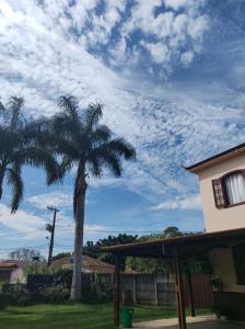 a palm tree next to a house with a cloudy sky at Pousada Santa Edwiges in Tiradentes