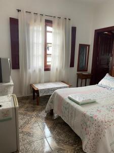 1 dormitorio con 2 camas, mesa y ventana en Pousada Santa Edwiges, en Tiradentes