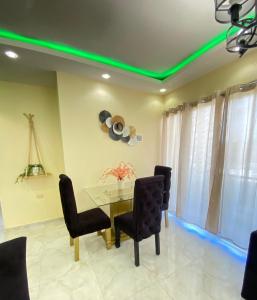 a dining room with a table and chairs with green lights at Acogedor apartamento in Santiago de los Caballeros