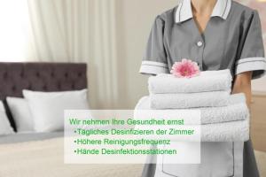 a woman holding a stack of towels in a hotel room at Aparthotel LAAERBERG in Vienna