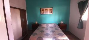 1 dormitorio con cama y pared verde en EL DESPERTAR, en Nueva Palmira