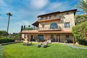 une grande maison en pierre avec des chaises sur une pelouse dans l'établissement Hameiri Estate, à Rosh Pinna