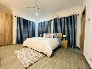 1 dormitorio con 1 cama con cortinas azules y alfombra en WellingManor Apartments - Luxury, en Accra
