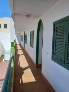 un couloir d'un bâtiment avec des fenêtres vertes dans l'établissement Las Islas Apartment, à Corralejo
