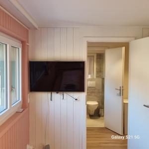 a bathroom with a flat screen tv on a wall at Mountain - Lake Apartment 3 in Wilderswil