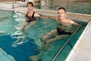 a man and a woman in a swimming pool at Résidence Thermotel in Bourbonne-les-Bains