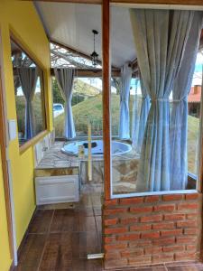 eine Whirlpool-Badewanne in einem Haus mit Fenstern in der Unterkunft Chalé Mirante Da Guapiara in Aiuruoca