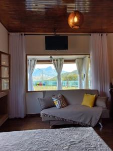 a living room with a couch and a large window at Chalé Mirante Da Guapiara in Aiuruoca