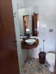 a bathroom with a sink and a toilet and a mirror at Chalé Mirante Da Guapiara in Aiuruoca