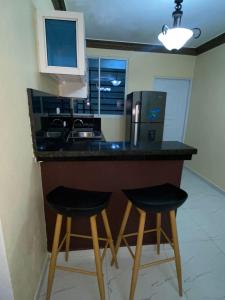 a kitchen with two stools at a counter with a refrigerator at Acogedor Apartamento in Santiago de los Caballeros