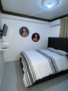 a bedroom with a bed with three pictures on the wall at Acogedor Apartamento in Santiago de los Caballeros