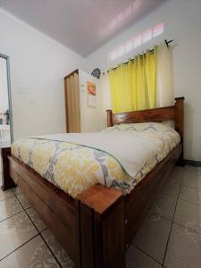 een slaapkamer met een houten bed en een geel gordijn bij Relax at Pier Sands Casita#1 - Close to the Beach! in Puntarenas