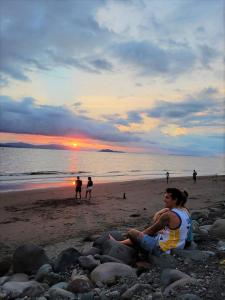 a woman sitting on the beach watching the sunset at Relax at Pier Sands Casita#1 - Close to the Beach! in Puntarenas
