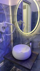 W łazience znajduje się biała umywalka i okrągłe lustro. w obiekcie B&B i Borboni w mieście Napoli