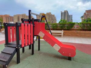 un parque infantil con un tobogán rojo en un parque en ACV - Torremar-2ª linea planta 5 frontal 3, en Oropesa del Mar