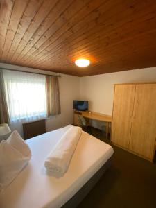 a bedroom with a white bed with a wooden ceiling at Gasthof Seiser in Straßburg in Kärnten