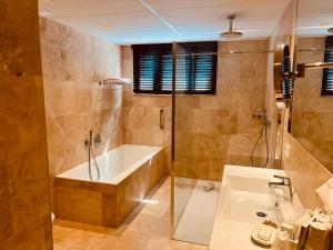 ein Badezimmer mit einer Badewanne und einem Waschbecken in der Unterkunft Gatsby Hotel - Adults Only - Small Luxury Hotel - by F-Hotels in Blankenberge