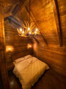 a bedroom with a bed in a wooden cabin with a chandelier at Hotel Tradita Valbonë in Valbonë