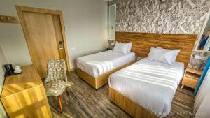a hotel room with two beds and a chair at Hotel Bankir Khiva in Khiva