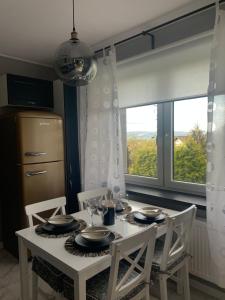 a dining room table with two chairs and a window at Apartament Słoneczny Świerkowa in Buczkowice