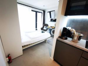 ein kleines Zimmer mit einem Bett auf einer Theke und einer Küche in der Unterkunft Hamburg 01 Modernes Apartment am Winterhuder Marktplatz Alster Stadtpark in Hamburg