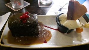 une assiette avec un morceau de gâteau et de crème glacée dans l'établissement The Grapes Hotel, à Newcastleton